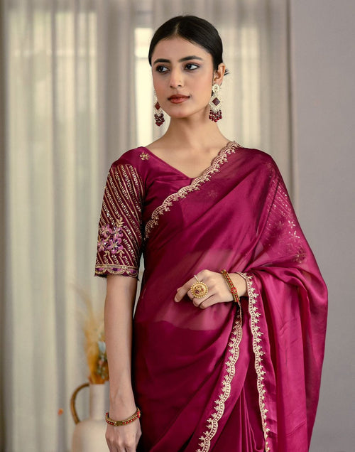 Woman wearing a deep magenta Graceful Rangoli Fabric Saree with a neat finish and comfortable drape, featuring intricate gold embroidery along the border and a matching blouse with detailed sleeve designs.